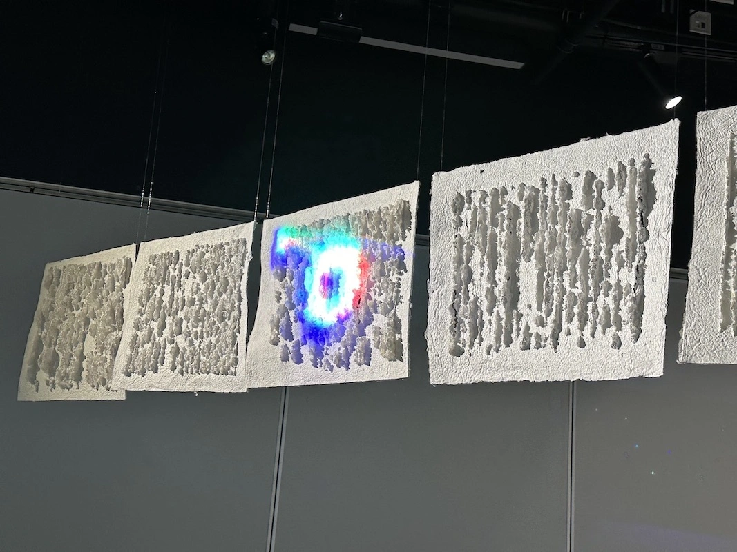 Suspended textural panels illuminated with dynamic light projections. The interplay of light and shadow creates an ethereal atmosphere.